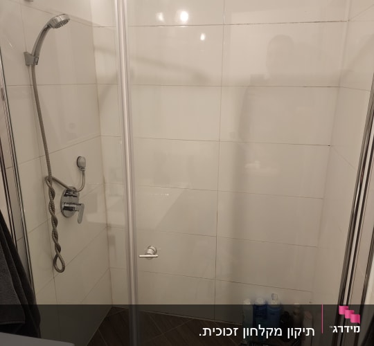 מקלחת עם בקבוקי שמפו וסבון על הרצפה